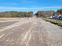 Long shot of graded dirt road, tress in distance.